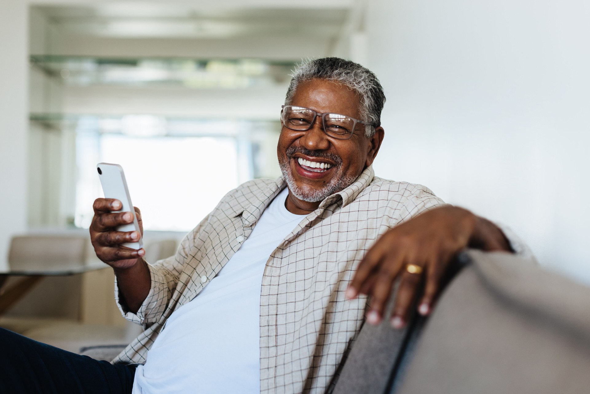 Cheerful man using technology at home, smiling and relaxing on the couch