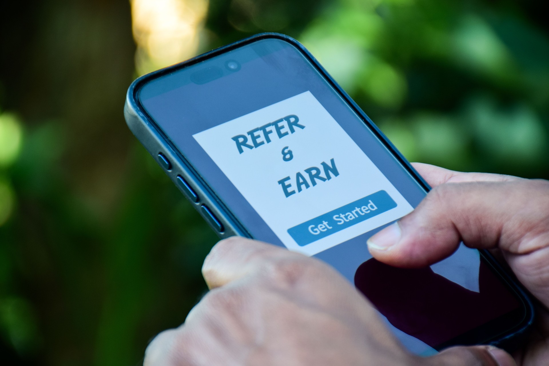 Smartphone displaying refer and earn program. Referral program to make money marketing strategy for increasing sales concept.